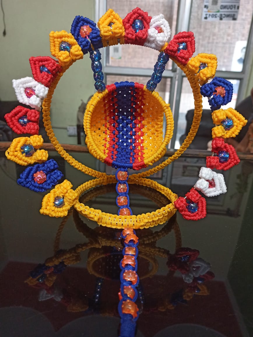 Macramé standing holder with coloured cords and beads, made by a woman beneficiary