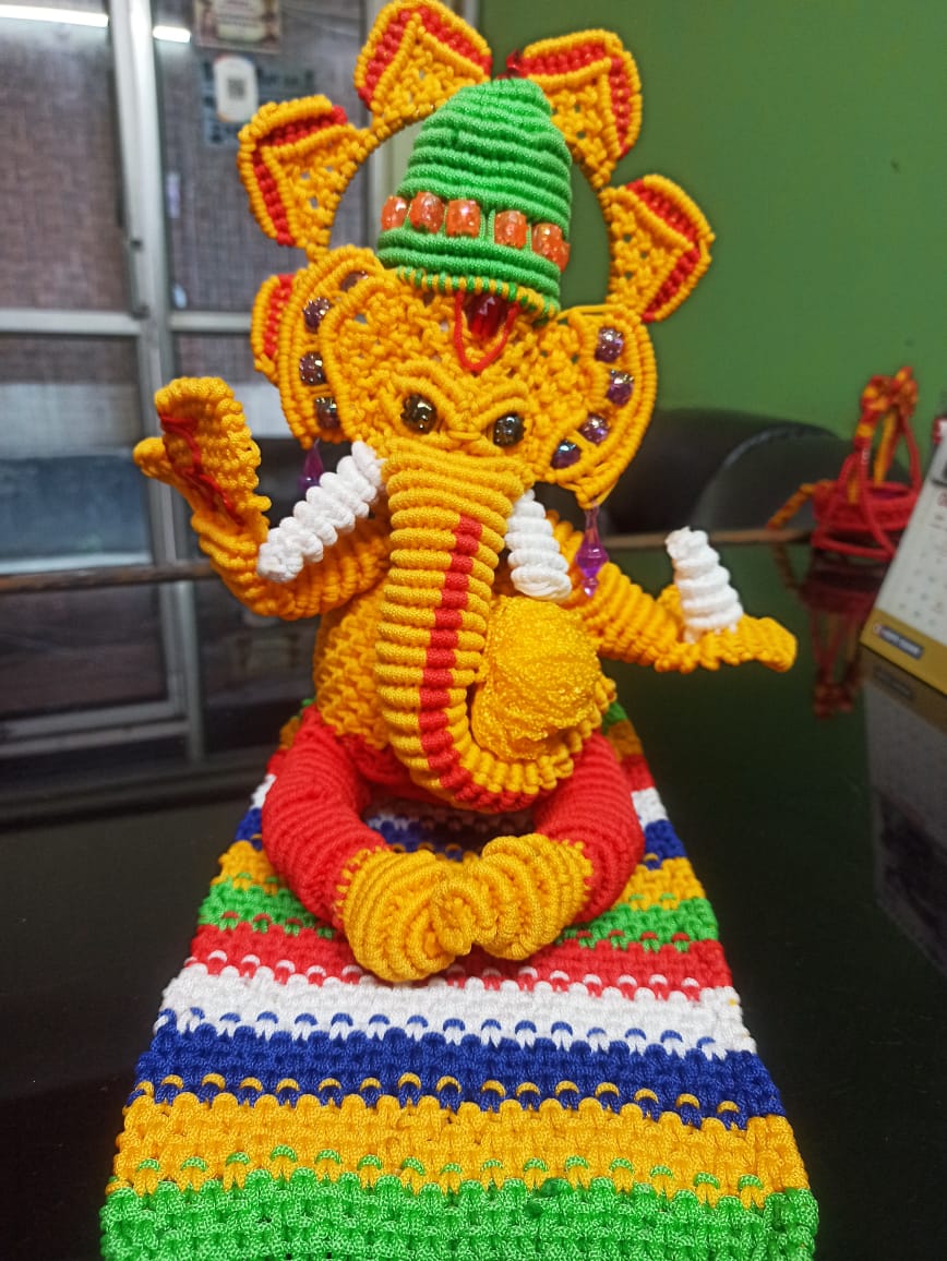 Macramé Lord Ganesha figurine seated on a woven striped base, made by a woman beneficiary