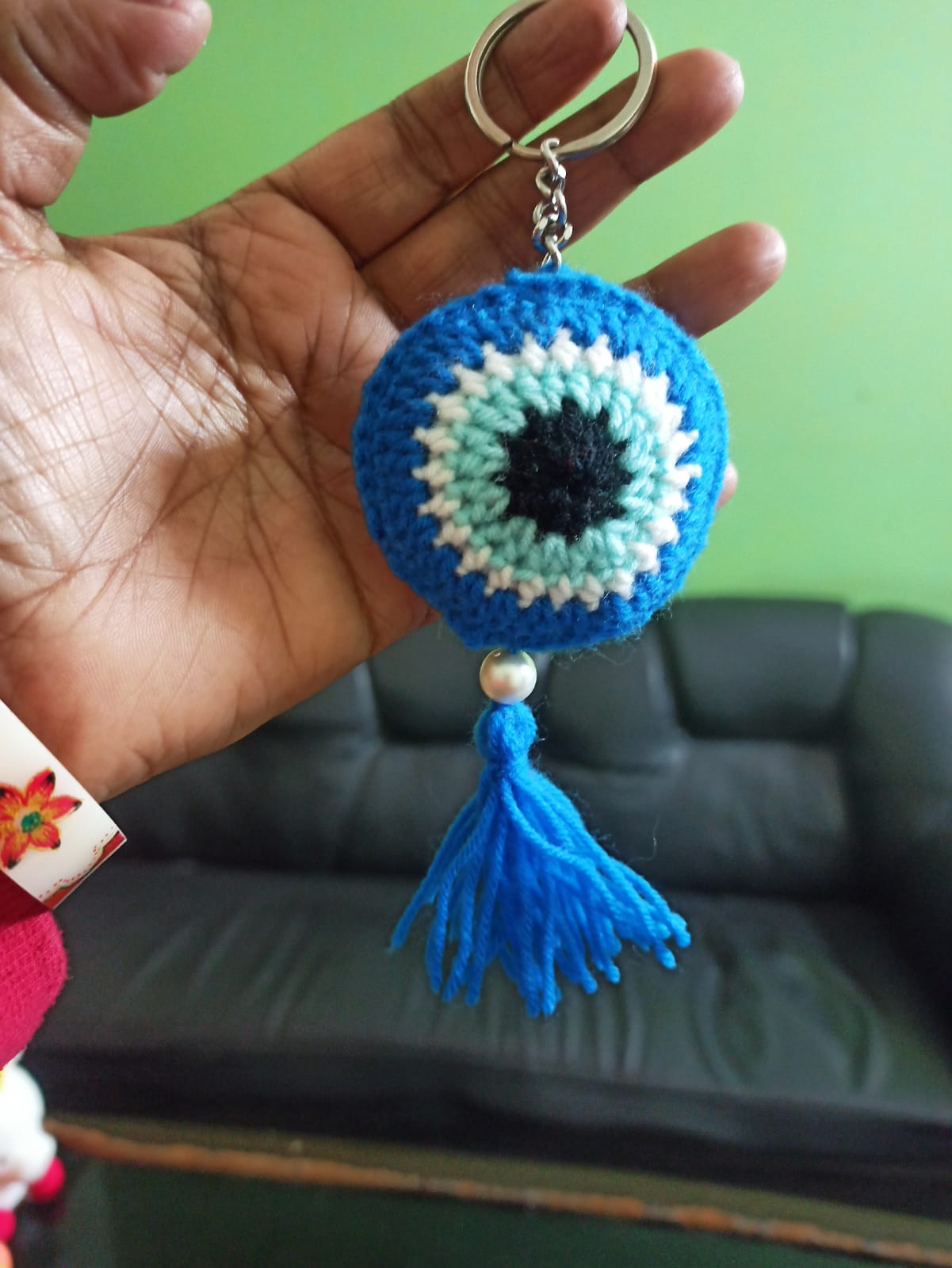Crocheted evil-eye keychain with a blue tassel, made by a woman beneficiary
